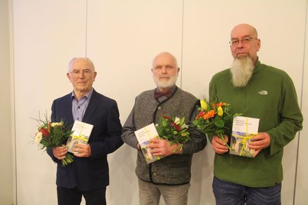 Die Autoren stehen aufgereiht von links nach rechts: Herr Heinz Henke, Herr Christoph Kretschmer und Friedhofsverwalter Herr Robert Eckhardt. Alle drei halten einen Blumengruß sowie das erschienene Buch als Präsent in der Hand.